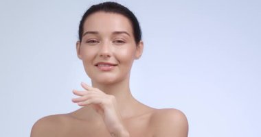 Zarif beyaz kadın yüzüne hafifçe dokunuyor ve ağır çekimde gülümsüyor. Cilt bakımı, güzellik ürünleri, yüz bakımı, sağlık ve kozmetik ürünleri için mükemmel..