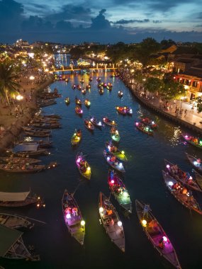 Gece vakti Hoi An nehrinde yüzen fener ışığında yanan teknelerin insansız hava aracı fotoğrafı. Seyahat, kültür ya da kutlama kavramları için mükemmel. Yüksek kalite ve canlı görüntüler.
