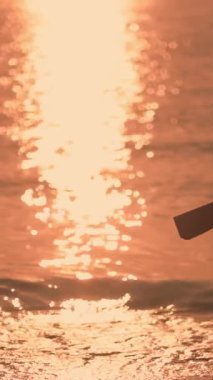 Silüetli bir kadın gün doğumunda elinde yoga minderiyle kumsalda yürüyor. Altın ışık ve huzurlu sahne refahı ve farkındalığı vurgular, yaşam tarzı ve uygunluğu için mükemmeldir.