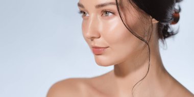 Parlak tenli, parlak dudaklı ve yumuşak ışıklı bir stüdyoda temiz makyajlı zarif bir genç kadın. Cilt bakımı, kaplıca, kozmetik reklamları, markalaşma ve güzellik kampanyaları için mükemmel..