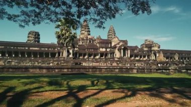 Hava aracı ağaçların ve yaprakların arasından doğruca Kamboçya 'daki Angkor Wat Tapınağı' na doğru uçuyor. Turizm tanıtımları, belgeseller ve destansı seyahatler için yüksek kaliteli sinematik görüntüler