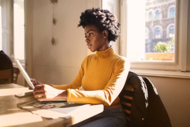 Genç güzel Afro kadın kamuya açık bir yerde bir gazete okuma.