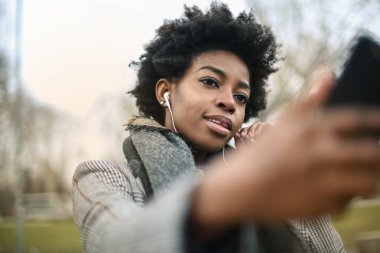 Genç güzel Afro bir kadın ile bir selfie alarak kulaklık.