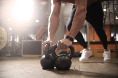 Bir su ısıtıcısı çan ile spor salonunda egzersiz yapan genç atletik erkek.