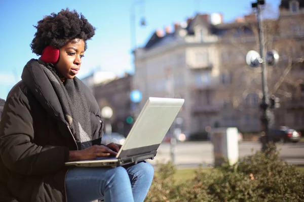 年轻美丽的非洲妇女坐在笔记本电脑和工作在街上 — 图库照片