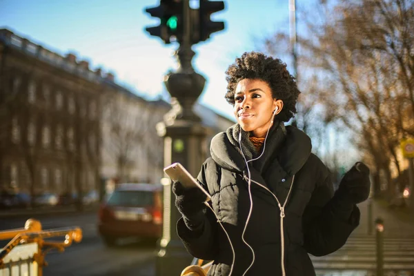 Νεαρή Όμορφη Γυναίκα Αφρο Ακουστικά Και Smartphone Περπάτημα Στην Πόλη — Φωτογραφία Αρχείου