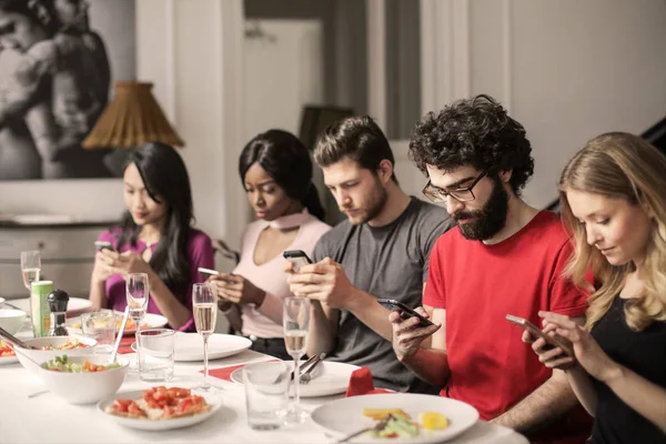 Grupo Amigos Jantando Casa Eles Verificando Seus Smartphones — Fotografia de Stock