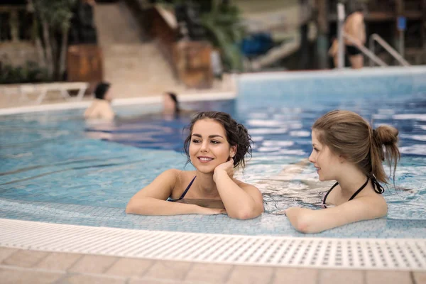 Açık bir spa havuz kenarındaki rahatlatıcı ve iyi vakit geçiren iki güzel genç kadın.