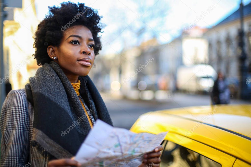 Young beautiful Afro woman wondering with a map in her hand.