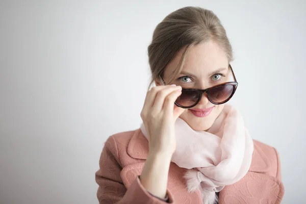 Young blonde woman in scarf and sunglasses smiling positively.