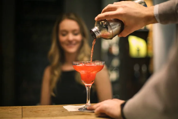 バーでかなりの女性の飲み物を注ぐバーテンダー — ストック写真