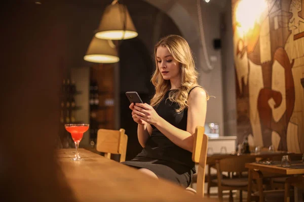 Mujer Joven Revisando Teléfono Inteligente Bar —  Fotos de Stock