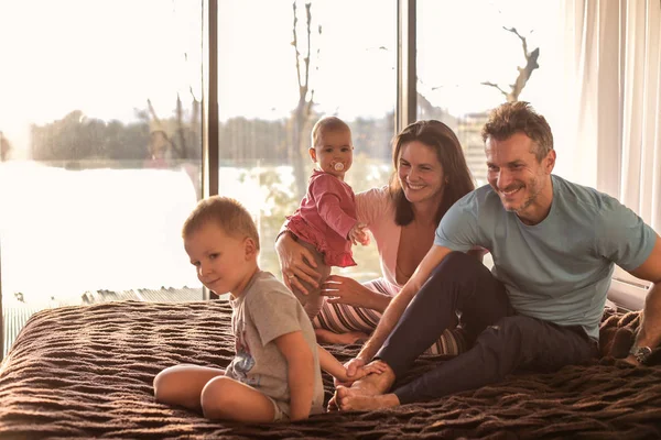 Familie Mit Zwei Kleinen Kindern Sitzt Auf Einem Bett Und — Stockfoto