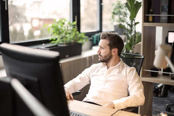 Junger Geschäftsmann Sitzt Seinem Schreibtisch Vor Seinem Computer Und Schaut — Stockfoto