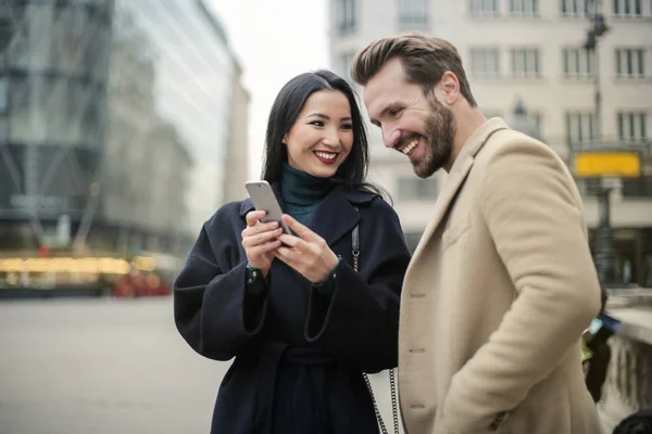 都市環境でスマート フォンを使用してスタイリッシュな若いカップルの笑顔 — ストック写真
