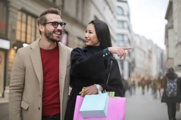 Happy young couple shopping on the street, thinking on going in one of the shops.