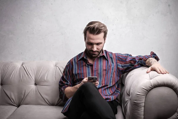 Giovane Uomo Affascinante Che Utilizza Suo Smartphone Divano — Foto Stock