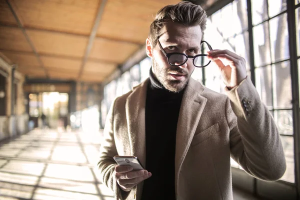 Giovane Con Uno Smartphone Che Toglie Gli Occhiali Interno Industriale — Foto Stock