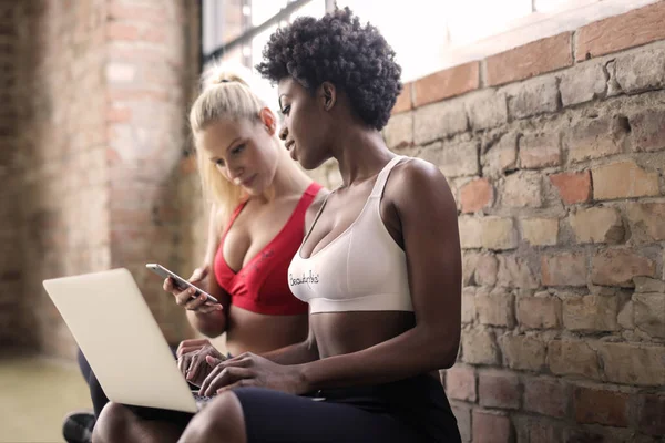 Två Flickor Gymmet Med Sin Mobiltelefon Och Bärbar Dator — Stockfoto