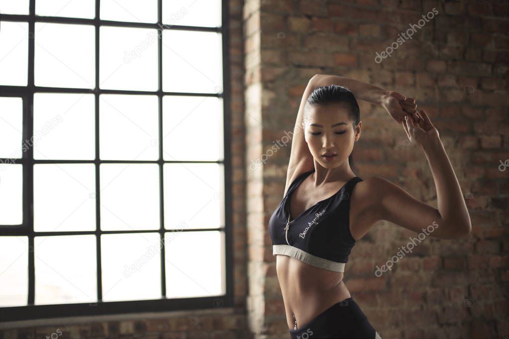 Young beautiful Asian woman stretching in the gym.