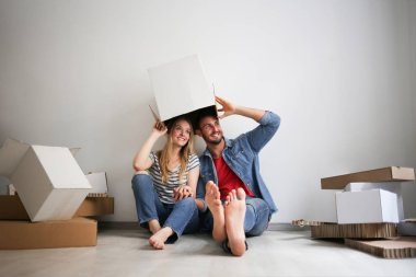 Genç mutlu çift şaka ve onların başının üstünde bir kağıt kutusu ile eğleniyor.