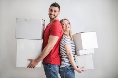 Birbirimizin arkasını için genç mutlu çift yaslanmış ve kağıt kutuları tutarak.