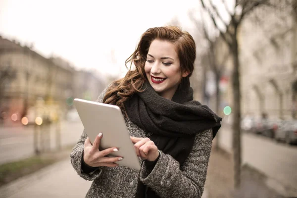 年轻美丽的妇女使用她的平板电脑在城市的街道上 — 图库照片