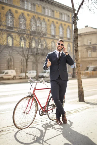 사업가와 선글라스 자전거 자세를 도시에서 스마트폰 이야기 — 스톡 사진