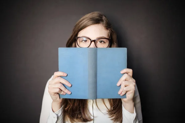 Giovane Donna Con Gli Occhiali Nasconde Dietro Suo Libro — Foto Stock