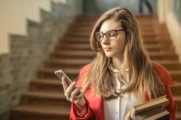 Młody Student Okulary Książki Sprawdza Jej Smartphone Korytarzu Uniwersytetu — Zdjęcie stockowe