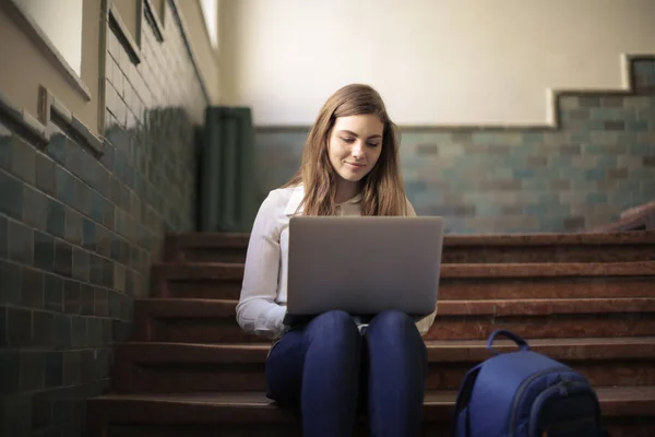 年轻女子坐在大学的楼梯上与她的笔记本电脑 — 图库照片