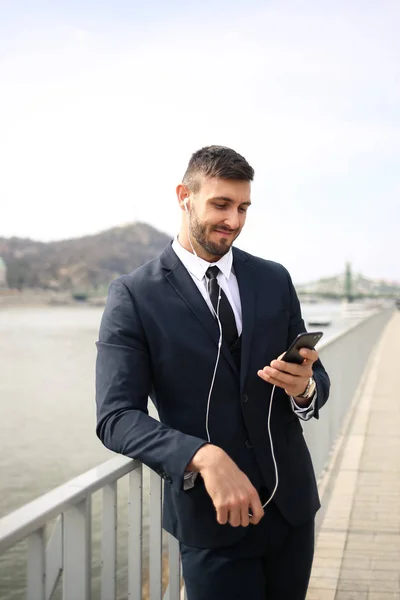 Joven Hombre Negocios Parado Puente Escuchando Música Smartphone —  Fotos de Stock