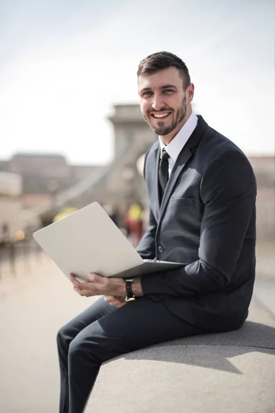 Junger Geschäftsmann Sitzt Mit Seinem Laptop Auf Einer Brücke Und — Stockfoto