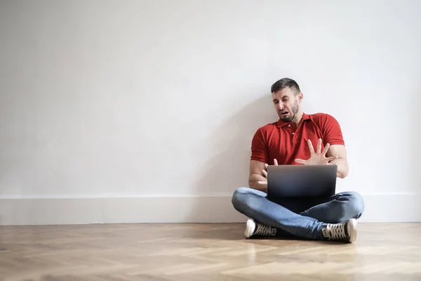 Jovem Sentado Chão Olhando Para Seu Laptop Com Nojo — Fotografia de Stock