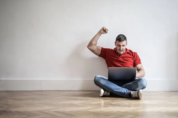 Jonge Man Zittend Vloer Kijken Naar Zijn Laptop Volkomen Gelukkig — Stockfoto