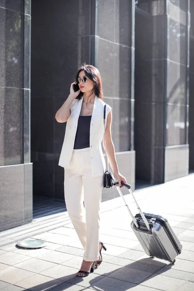 Asya şık iş kadını sokakta onun Smartphone cep telefonu ile konuşurken bir çanta.
