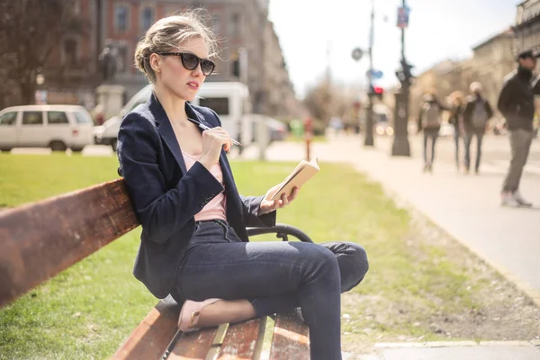Şehirde bir bankta oturmuş ve onun gündem kontrol genç güzel kadın.