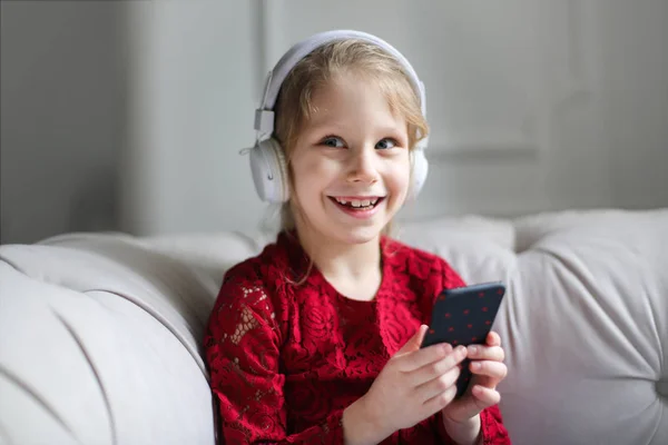 若い女の子は 笑みを浮かべて彼女の頭と彼女の手でスマート フォン上のヘッドフォン — ストック写真