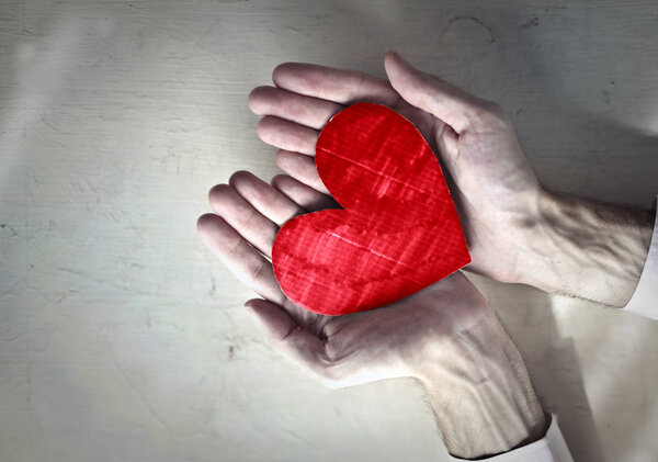 Hand with a red paper heart.