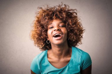 Gülüyor ve kameraya gülümseyen genç Afro kadın.