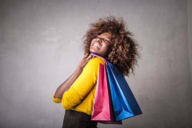 Mutlu bir şekilde onun elinde alışveriş torbaları ile gülümseyen genç Afro kadın.