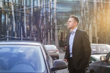 İşadamı şehir arabasında yanında ayakta.