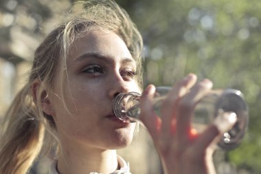 Sarışın genç kadın içme suyu güneşli bir günde.