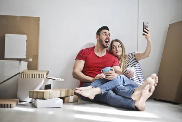 Young couple sitting on the floor and taking selfie.