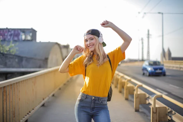 Young blonde teenager with baseball hat dancing on the street.