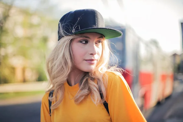 Young blonde teenager with baseball hat in the city.
