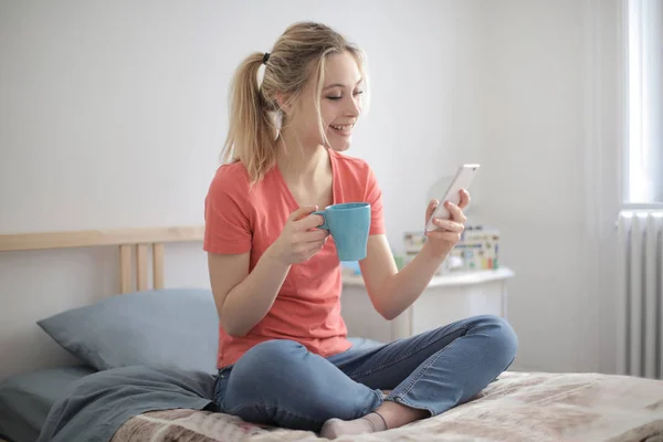 Молода Блондинка Сидить Ліжку Кавою Перевіряє Свій Смартфон — стокове фото