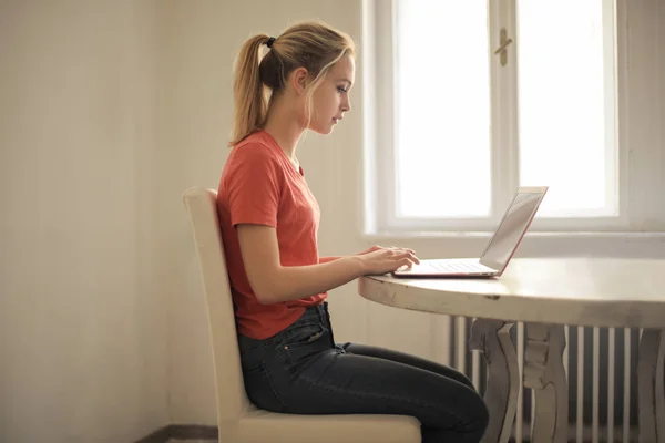 年轻的金发女郎坐在办公桌前 在她的笔记本电脑上工作 — 图库照片