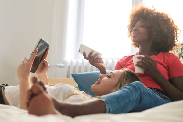 Dos Amigas Jóvenes Divierten Una Cama Casa Revisan Tableta Teléfono —  Fotos de Stock