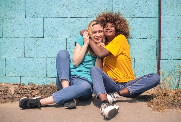 Two Young Female Friends Sitting Next Blue Wall Hugging Summer — Stock Photo, Image